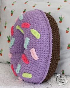 a purple crocheted bag sitting on top of a bed next to a pillow