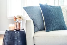 a living room with a couch, coffee table and vase on the end table in front of it