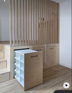 an empty room with wooden stairs and storage cabinets on the wall, in front of a staircase