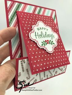 a hand holding up a christmas card with the words happy holidays on it's side