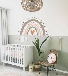 a baby's room with a white crib, wicker chair and potted plant