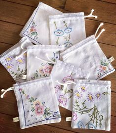 six embroidered napkins with flowers on them sitting on a wooden table next to each other