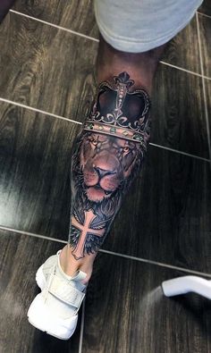 a lion with a crown tattoo on his leg