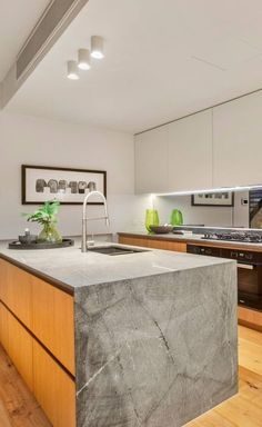 a large kitchen with an island in the middle and wood flooring on the other side