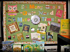 a bulletin board with many books on it and an owl clock mounted to the wall