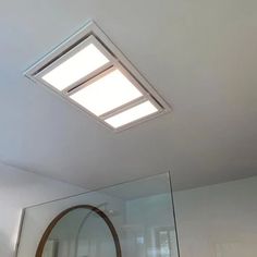 a bathroom with a skylight above the sink and mirror on the wall next to it