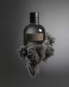 a bottle of perfume with fur on it's cap and the label is black