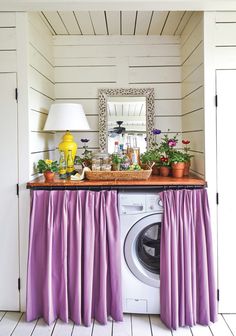 a washer and dryer in a room with flowers on the counter, potted plants next to it