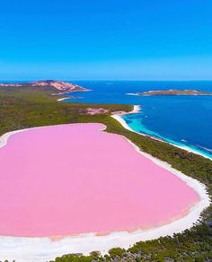 an aerial view of a pink lake in the middle of nowhere, surrounded by blue water