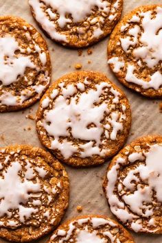 several cookies with white icing and sprinkles are on a piece of parchment paper