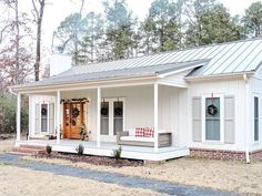 a white house with a red checkered pillow on the porch and wreaths hanging from the front door