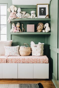 there are stuffed animals sitting on the shelves in this green room with pink and white pillows