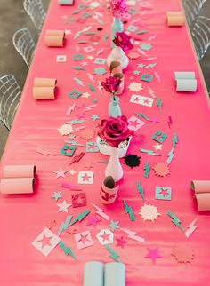 a long pink table with confetti and paper stars on the top, along with candles