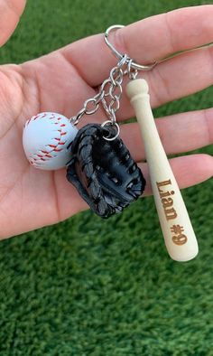 a baseball bat, glove and ball on a keychain that is in someone's hand