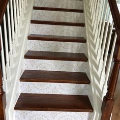 a set of wooden stairs leading up to a second story room with white walls and wallpaper