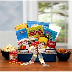 a gift basket filled with snacks and candy sits on a table next to a bowl of popcorn