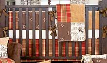 a baby crib is decorated with brown and white plaid blankets, bows, and pillows