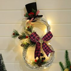 a christmas wreath hanging from the wall with lights and decorations on it's sides