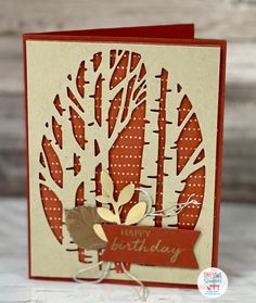 a handmade birthday card with an autumn tree on the front, and a red ribbon around it