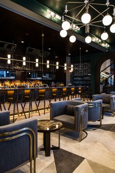 a restaurant with chairs, tables and lights hanging from the ceiling above it's bar