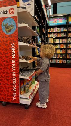 a little boy that is standing in front of a book shelf