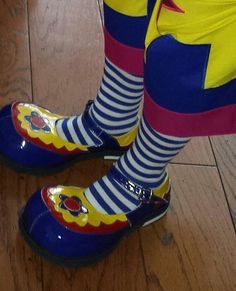 the legs and feet of a person in colorful shoes on a wooden floor with striped socks