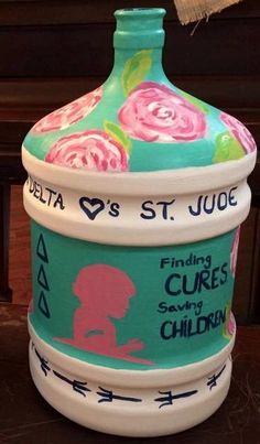 a ceramic jar that has been decorated with flowers and writing on the side, sitting on a table