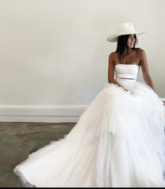 a woman in a white dress and hat sitting on a chair