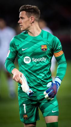 a soccer player is holding his gloves on the field