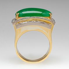 This exquisite platinum topped 18K yellow gold ring is centered with one (1) oval cabochon cut natural jadeite jade set into a four-prong head and is bordered with thirty (30), bead set, round brilliant cut diamonds and twelve (12), channel set, baguette cut diamonds. The ring measures 18.4mm at the top, rises 10.3mm above the finger, tapering to 5.2mm wide and 1.3mm thick at the base of the shank. The ring is currently a size 6.25 and we offer complimentary sizing to fit. Elegant Jade Rings With Cabochon, Elegant Jade Cabochon Rings, Elegant Emerald Jade Ring With Cabochon, Fine Jewelry Jade Rings With Polished Finish, Elegant Oval Chrysoprase Rings, Luxury Jade Ring For Formal Occasions, Modern Oval Jade Ring, Elegant Chrysoprase Emerald Ring For Anniversary, Elegant Yellow Gold Jade Rings