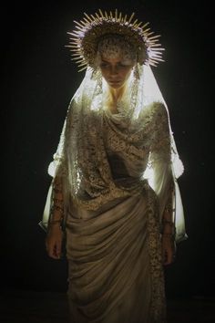 a woman dressed in an elaborate dress and headdress with lights shining on her face