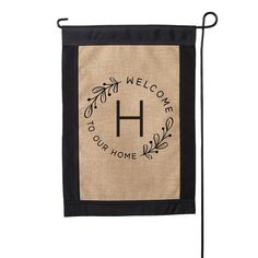 a black and tan welcome home flag with the letter h on it's side