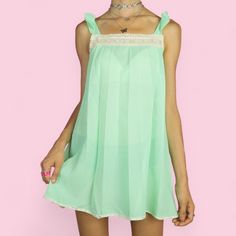 The Vintage 60s Babydoll Dress is a charming pastel mint green, semi-sheer slip mini dress featuring delicate pleats, lace detailing across the front, and sweet bows on the straps. This flowy, romantic nightdress is perfect for lounging and sleepwear. SIZE S MEASUREMENTS Length 70cm - 27.56 inch Chest 88cm - 34.65 inch Our model is 172 cm tall and usually wears size XS.  We ship worldwide from Spain and offer free shipping on all orders when you buy 3 items or more! ♥ https://adultworldshop.etsy Green Ruffled Mini Dress For Daywear, Sheer Coquette Summer Dress, Sleeveless Coquette Mini Dress For Daywear, Feminine Green Dress With Lace Trim, Feminine Green Dresses With Lace Trim, Feminine Green Mini Dress For Daywear, Coquette Sheer Mini Dress For Summer, Cute Green Daywear Dress, Green Sheer Mini Dress For Summer