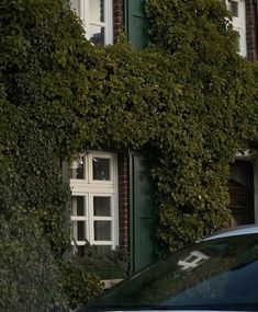 a car is parked in front of a building covered with green plants and ivys