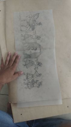 a person holding up a piece of paper with drawings on it and another drawing in the background