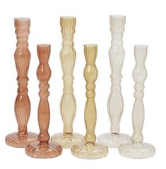 four different colored glass candlesticks on a white background