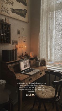 a desk with a laptop on top of it next to a window and a chair