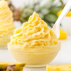 a bowl filled with pineapple ice cream next to slices of pineapple