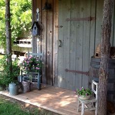 a wooden porch with potted plants on it and a bench in the foreground