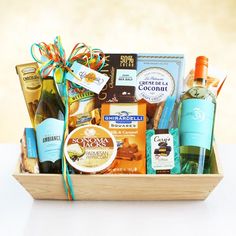 a wooden basket filled with lots of different types of food and wine bottles on top of a table