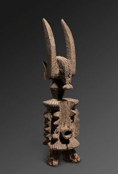 an ancient statue with two large horns sticking out of it's back end, against a gray background