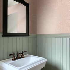 a white sink sitting under a bathroom mirror next to a wooden wall mounted faucet