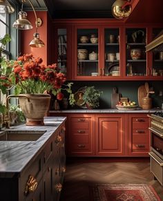 a kitchen with red cabinets and flowers in vases on the counter top next to an oven