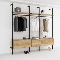 an open closet with clothes and shoes hanging on the wall, next to a shoe rack