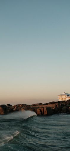 a lighthouse on top of a rock outcropping in the ocean with waves