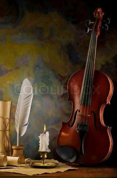 an old violin, feather quill and candle on a table