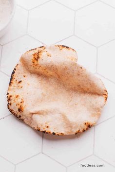 an old tortilla is sitting on the floor next to a glass of milk