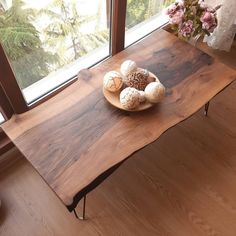 a wooden table topped with lots of different types of eggs on top of it next to a window