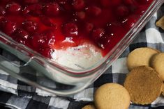 a dessert dish with cherries in it and crackers on the table next to it