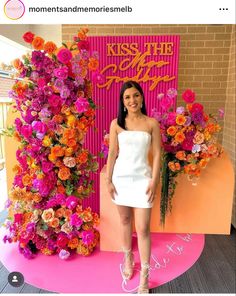 a woman standing in front of a pink and orange flower display with flowers on it